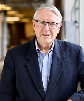 Prof. Ned Thomas stands in front of a blurred corridor